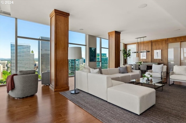 living room featuring expansive windows, dark wood-type flooring, a wealth of natural light, and ornate columns