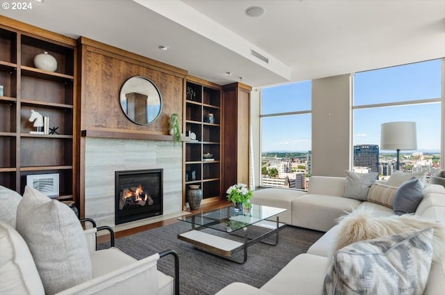 living room featuring a tile fireplace, hardwood / wood-style flooring, floor to ceiling windows, and built in features