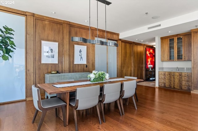 dining area with wood walls and wood-type flooring