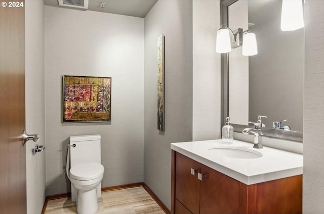 bathroom with hardwood / wood-style flooring, vanity, and toilet