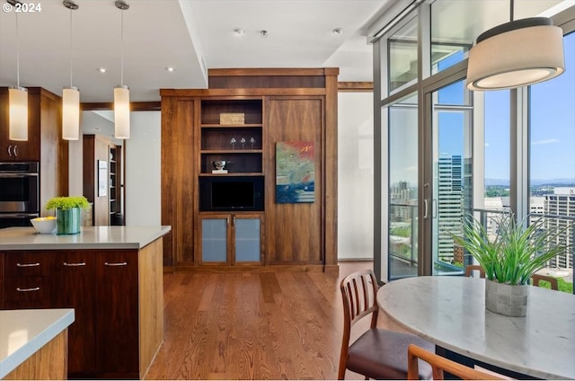 kitchen featuring a healthy amount of sunlight, a wall of windows, decorative light fixtures, and hardwood / wood-style flooring