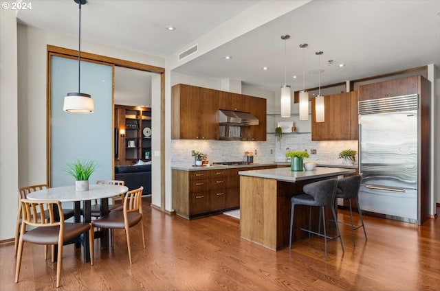 kitchen featuring pendant lighting, a center island, stainless steel appliances, dark hardwood / wood-style flooring, and a kitchen breakfast bar