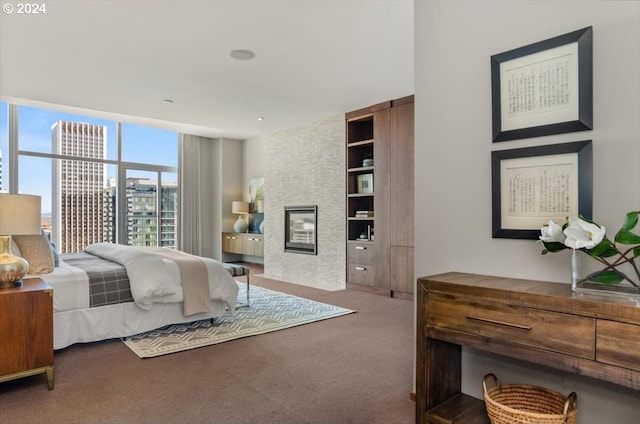 bedroom featuring carpet floors, floor to ceiling windows, and a fireplace