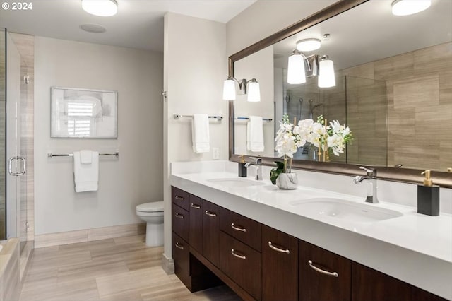 bathroom featuring toilet, tile patterned flooring, a shower with door, and vanity