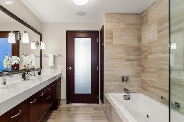 bathroom featuring a relaxing tiled tub and vanity