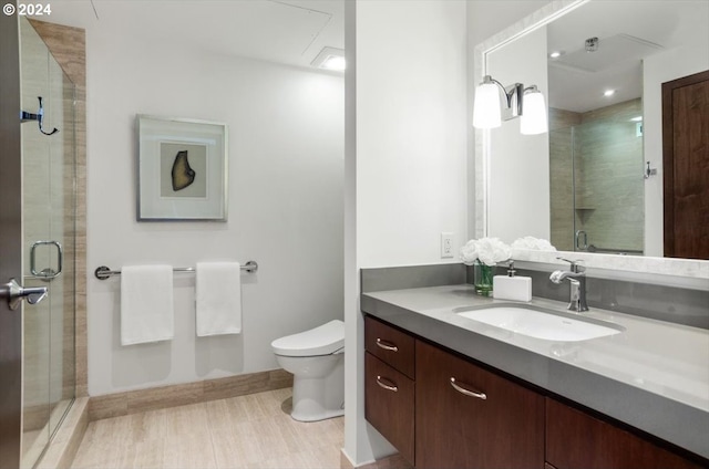 bathroom featuring toilet, a shower with door, and vanity