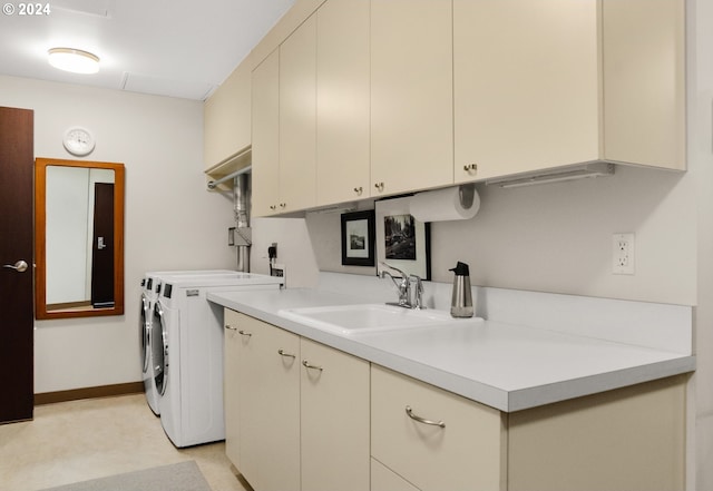 laundry room with sink, washing machine and dryer, and cabinets