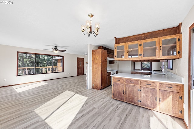 kitchen featuring ceiling fan with notable chandelier, light wood-type flooring, hanging light fixtures, and sink