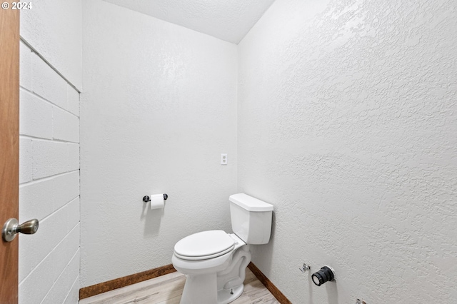 bathroom featuring wood-type flooring, a textured ceiling, and toilet