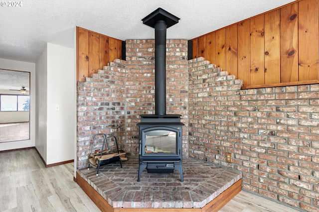 room details with a textured ceiling, hardwood / wood-style floors, and a wood stove