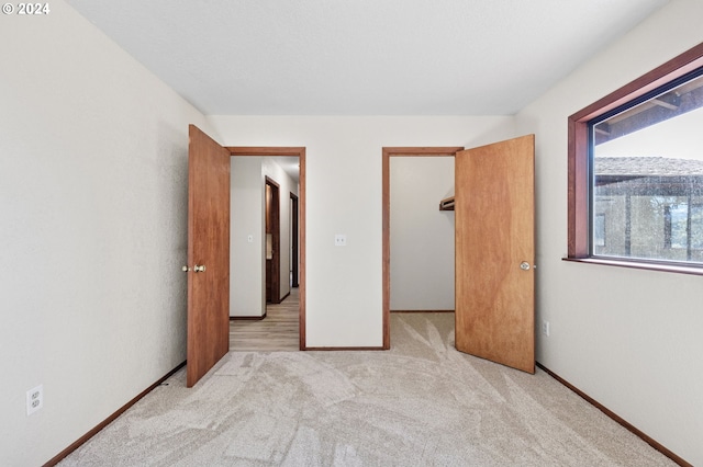 unfurnished bedroom with light carpet, a spacious closet, and a closet