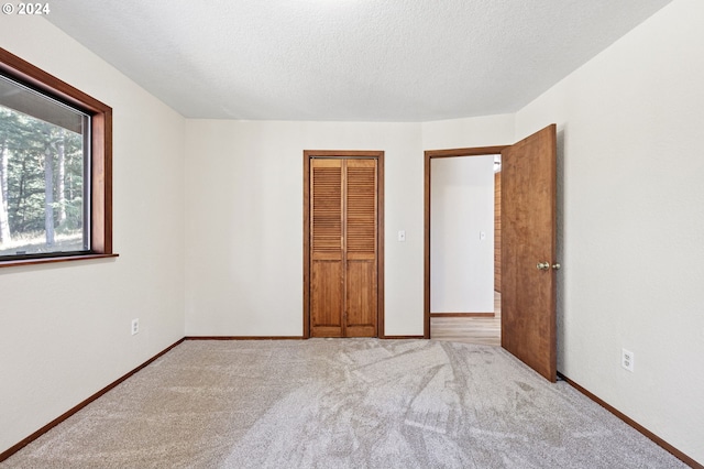 unfurnished bedroom with a closet, light colored carpet, and a textured ceiling