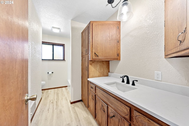 bathroom with a textured ceiling, hardwood / wood-style flooring, vanity, and toilet