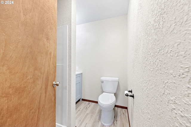 bathroom with toilet, hardwood / wood-style floors, and vanity