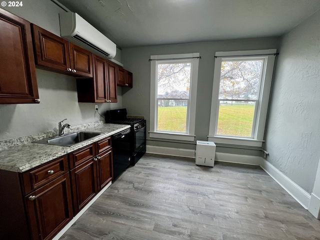 kitchen with a wall mounted air conditioner, light wood-type flooring, black appliances, and sink