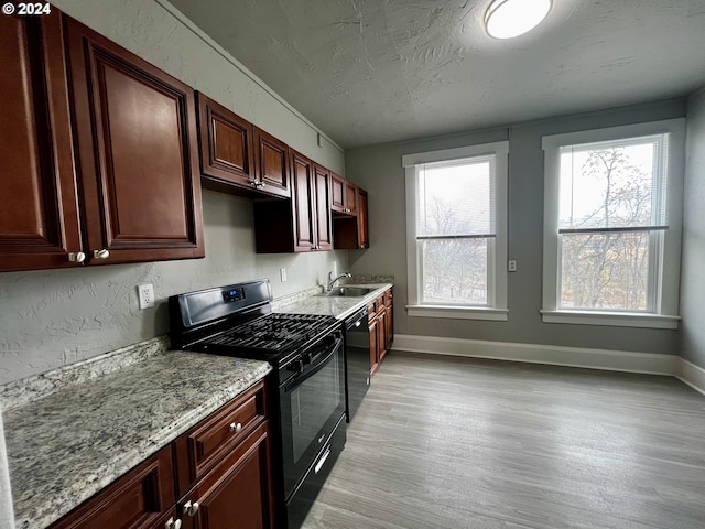 kitchen featuring light stone countertops, sink, light hardwood / wood-style flooring, a textured ceiling, and black appliances