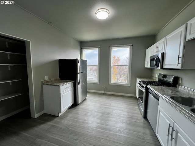 kitchen featuring sink, light wood-type flooring, white cabinetry, and stainless steel appliances