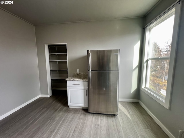 401 NW Bailey Ave, Pendleton, OR 97801 - kitchen featuring freestanding refrigerator, wood finished floors, white cabinetry, baseboards, and light stone countertops