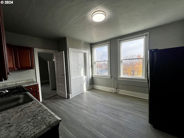 kitchen featuring light wood-type flooring, black fridge, and sink