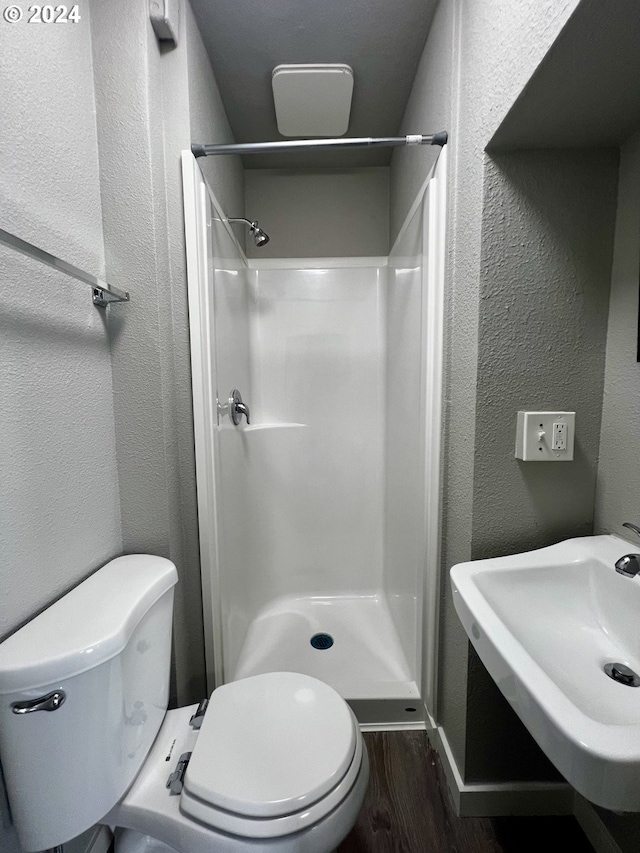 bathroom featuring a shower, sink, wood-type flooring, and toilet