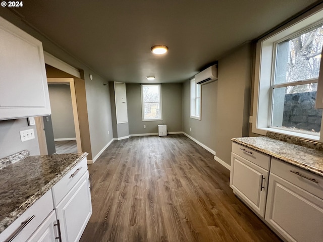 unfurnished dining area featuring a wall mounted AC and hardwood / wood-style flooring