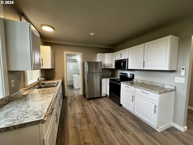 kitchen with light stone countertops, appliances with stainless steel finishes, sink, hardwood / wood-style flooring, and white cabinetry