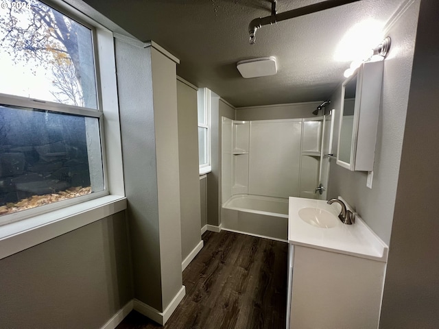 bathroom with vanity, a textured ceiling, hardwood / wood-style flooring, and bathing tub / shower combination