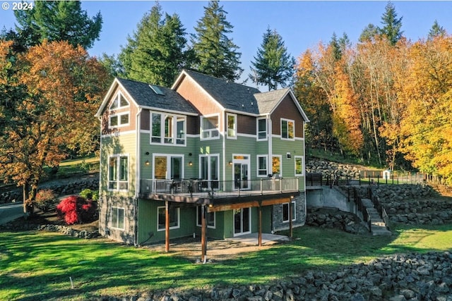 back of property featuring a deck and a lawn