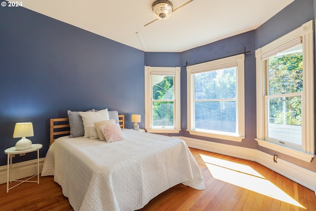 bedroom with multiple windows and dark hardwood / wood-style floors