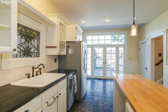 kitchen with decorative light fixtures, butcher block countertops, french doors, sink, and white cabinets