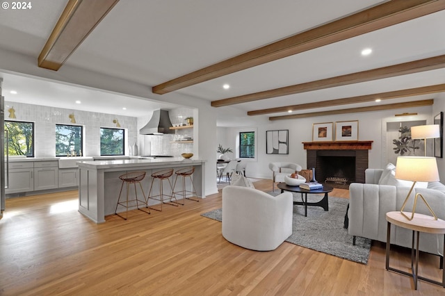 living room featuring beamed ceiling, light hardwood / wood-style flooring, and a fireplace