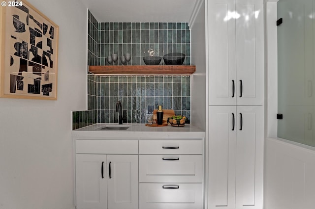 bar with sink, white cabinets, and tasteful backsplash