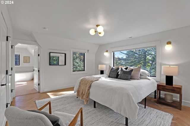 bedroom with multiple windows, ensuite bathroom, and light parquet floors