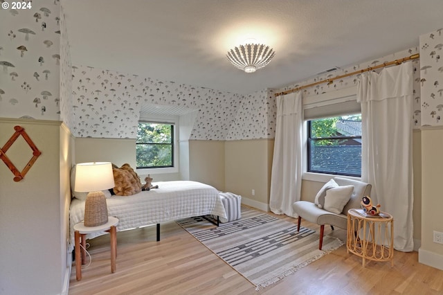 bedroom with light hardwood / wood-style floors, multiple windows, and a textured ceiling