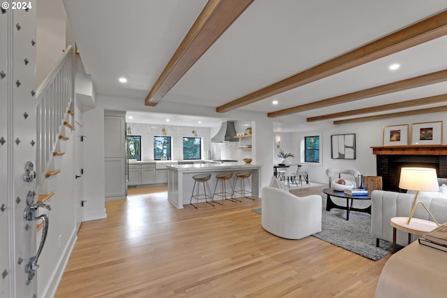 living room featuring light hardwood / wood-style floors, beam ceiling, and a fireplace