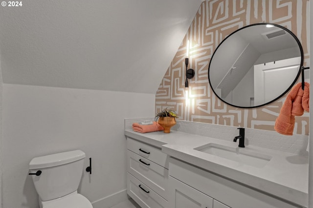 bathroom with vanity, toilet, and vaulted ceiling