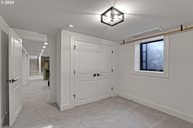 unfurnished bedroom featuring light carpet, a closet, and a textured ceiling