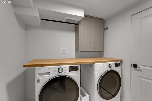 laundry room featuring separate washer and dryer and cabinets