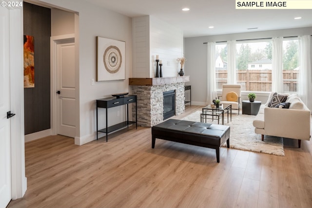 living room with light wood-type flooring and a stone fireplace