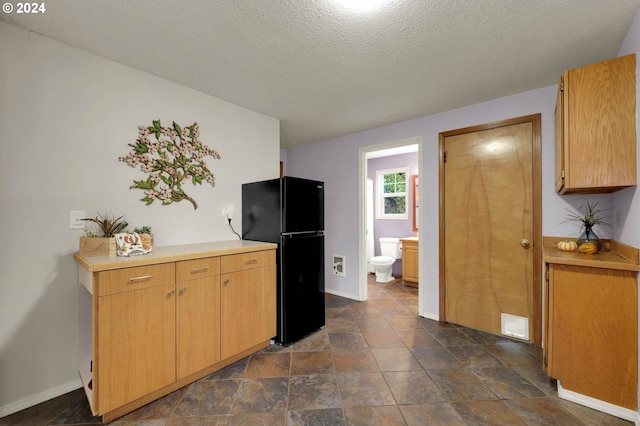 kitchen with black fridge and a textured ceiling