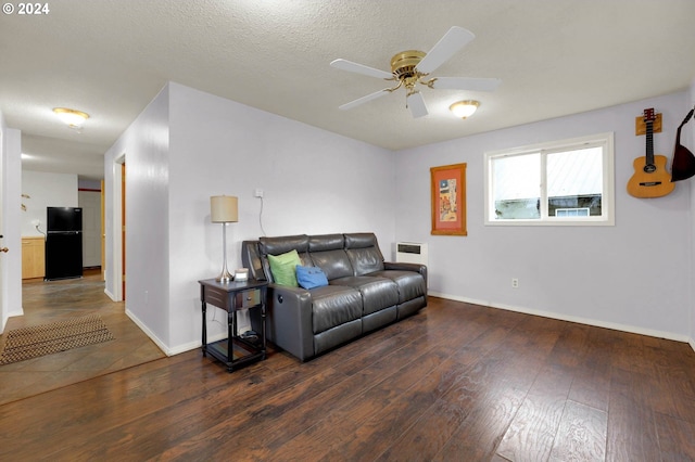 living room with a textured ceiling, dark hardwood / wood-style flooring, and ceiling fan