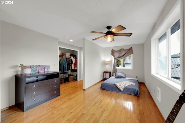 bedroom with ceiling fan, a spacious closet, light hardwood / wood-style flooring, and a closet