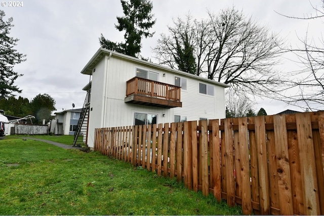 back of property with a lawn and a balcony