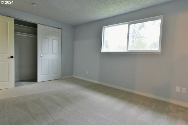 unfurnished bedroom with light carpet, a closet, and a textured ceiling