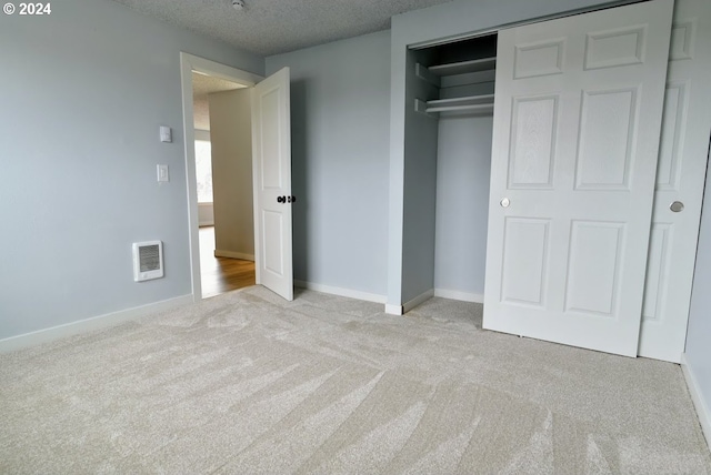 unfurnished bedroom with a textured ceiling, heating unit, light carpet, and a closet