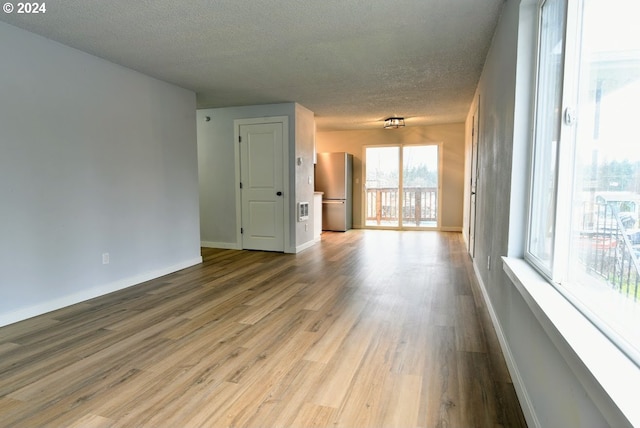 unfurnished living room with a textured ceiling and light hardwood / wood-style floors