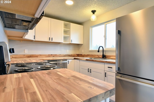 kitchen featuring appliances with stainless steel finishes, white cabinetry, butcher block counters, a textured ceiling, and sink