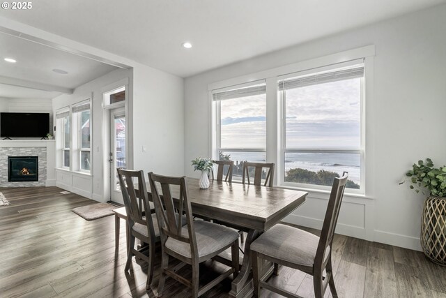 dining room with hardwood / wood-style flooring, a water view, and a fireplace