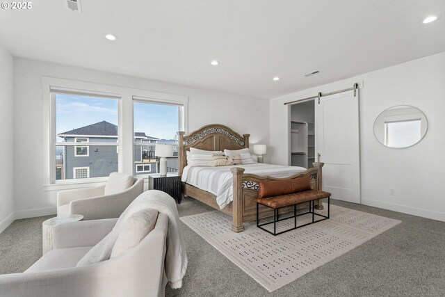 carpeted bedroom with a walk in closet and a barn door