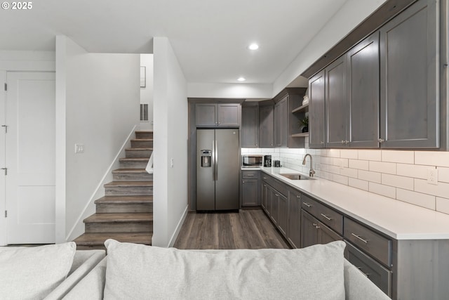 kitchen with built in microwave, dark wood-type flooring, sink, stainless steel fridge, and backsplash